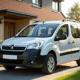 Voiture Peugeot Partner 5 places devant maison moderne en plein jour